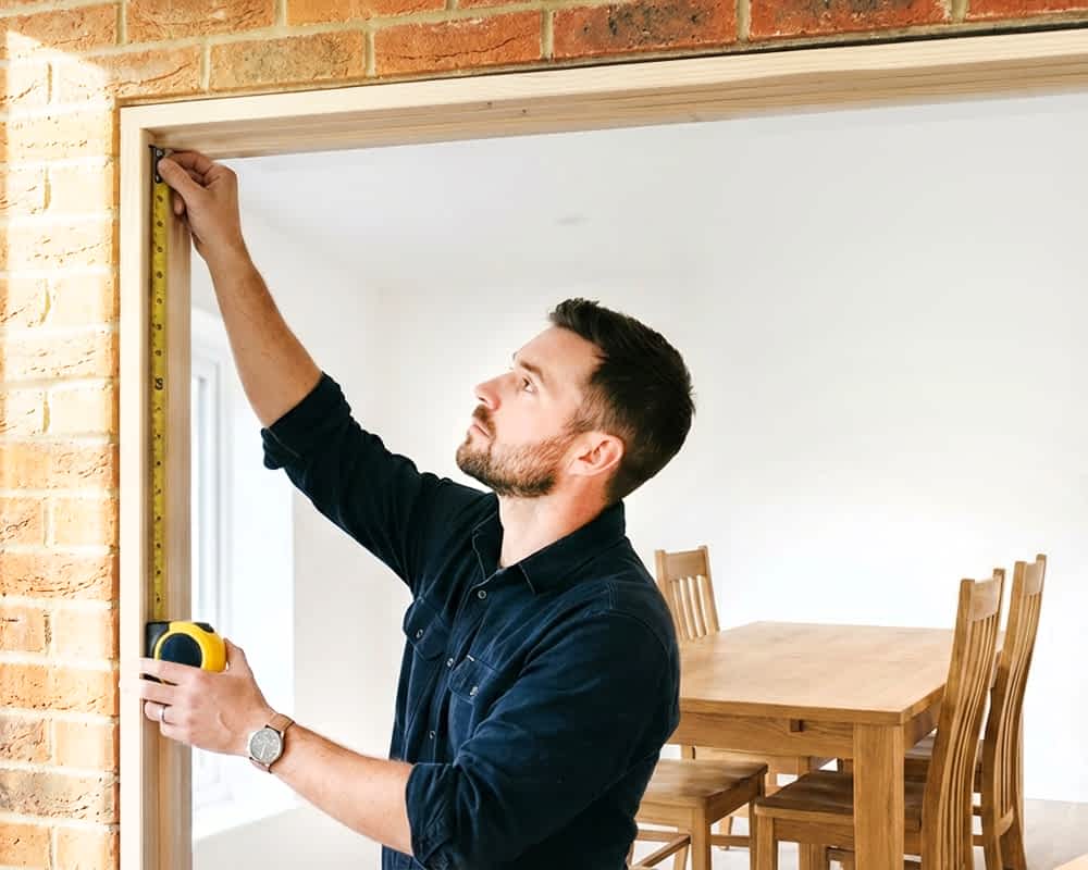 A man measuring an external door frame