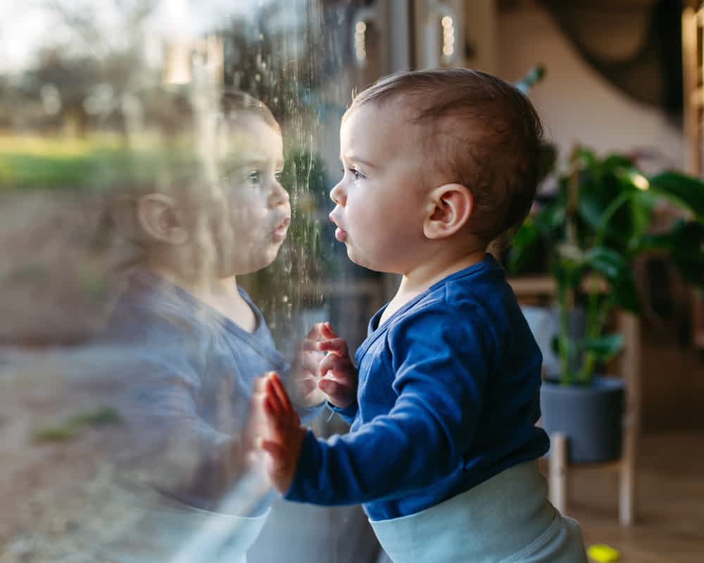 A toddler standing at a patio door