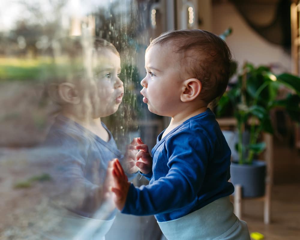 A toddler standing at a patio door