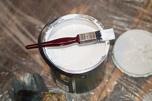 A white tin of paint and paint brush