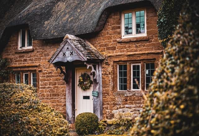 thatched roof cottage with white front door adorned with ivy wreath