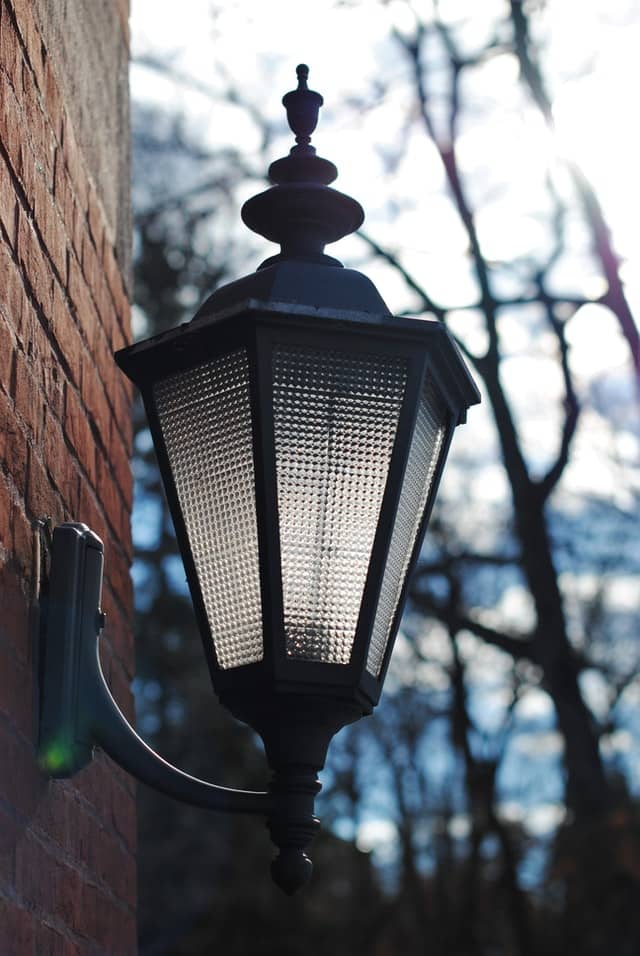 outdoor light attached to a brick wall, with 6 glass panes encased in aluminium black frame